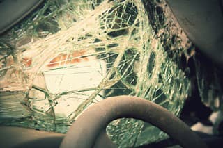 Close op of the steering wheel and shatterd windshield of a wrecked vehicle.  Cross processing.