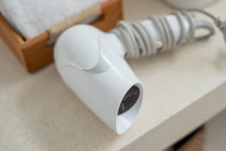 Close-up flatlay shot of white hair dryer and folded clean towel above bathroom counter at luxury villa in Bali