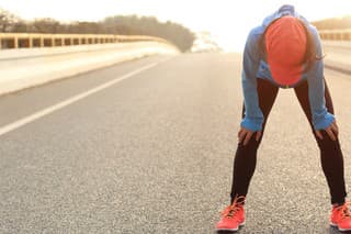 tired woman runner taking a rest after running hard on city road