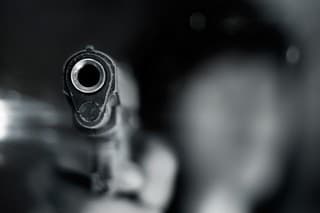 Black and white, woman pointing a old gun to front with one Hand on dark background