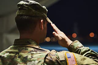 Rearview shot of a young soldier standing at a military academy and saluting