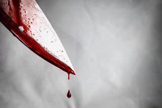 close-up of man holding knife smeared with blood and still dripping.