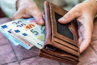 Pensioner woman holding in hands wallet with money.