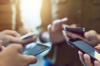 Cropped shot of a group of colleagues using their smart phones in synchronicity