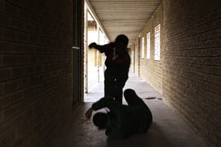 Two school kids fight in a dark passageway of their school, almost silhouette.