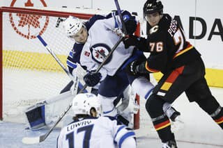 Neal Pionk (Winnipeg) a Martin Pospíšil (Calgary) v súboji pred bránkou.