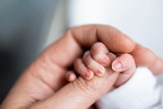 hand of newborn baby who has just been born holding the finger of his father's hand.