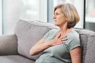 Shot of a senior woman suffering from chest pain while sitting on the sofa at home