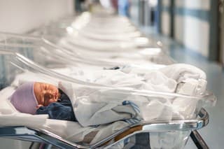 Newborn baby boy in his small transparent portable hospital bed