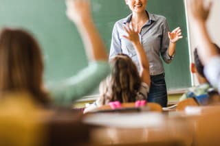 Happy female teacher asked a question during a class at elementary school.