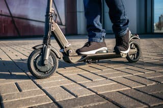 Close up view of legs of man on electric scooter outdoor.