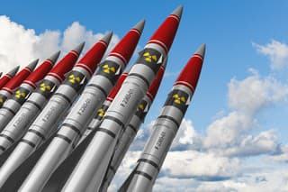 Row of heavy nuclear missiles against blue sky with clouds. See also: