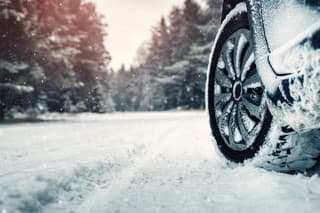 Car tires on winter road covered with snow. Vehicle on snowy way in the morning at snowfall