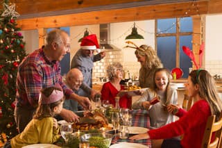 A large family are all helping serve Christmas dinner.