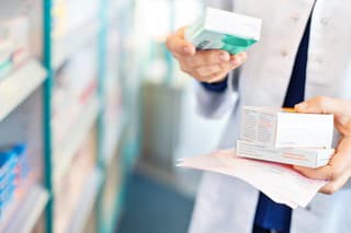 Closeup of pharmacist's hands taking medicines from shelf at the pharmacy