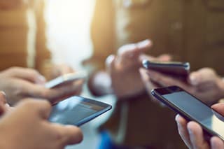 Cropped shot of a group of colleagues using their smart phones in synchronicity