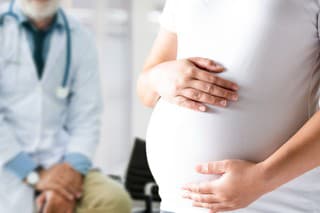 Happy pregnant woman visit gynecologist doctor at hospital or medical clinic for pregnancy consultant. Doctor examine pregnant belly for baby and mother healthcare check up. Gynecology concept.
