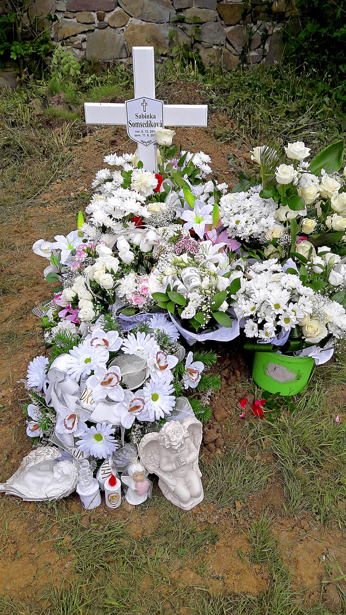 Hrobček zasypali biele kvety.