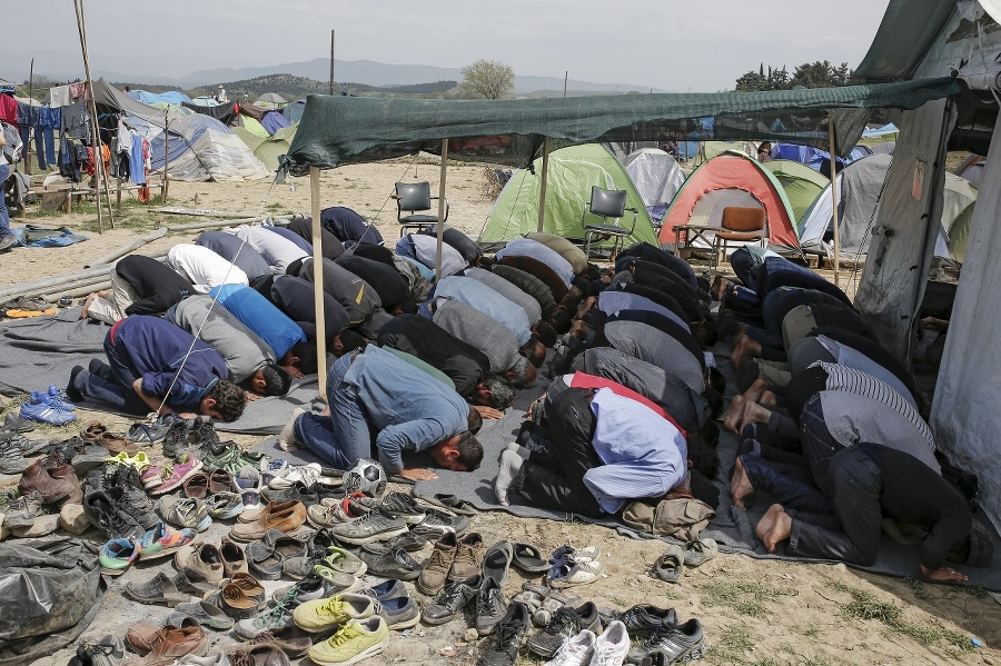 Migranti počas modlitby v