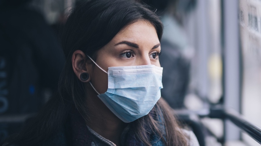 Young woman wearing protective face mask, she sitting in bus transportation in the city.