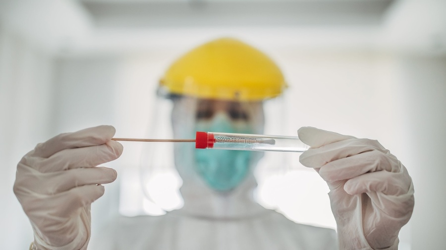 On woman, female doctor in protective suit holding and showing covid-19 tube test and sampling swab.