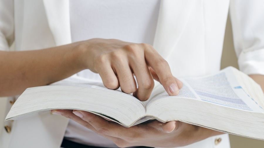 closeup of woman’s hands skimming through a dictionary 