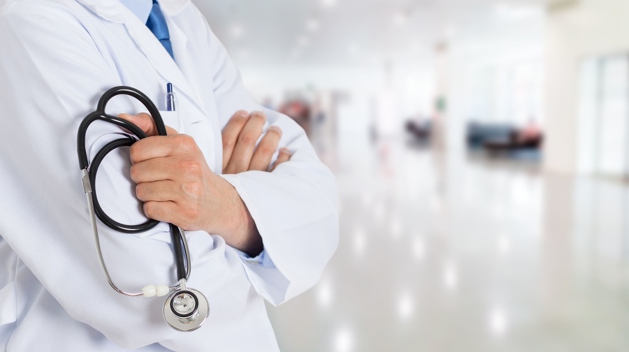 Cropped shot of an unrecognizable male doctor standing with his arms folded inside of a hospital during the day and copy space