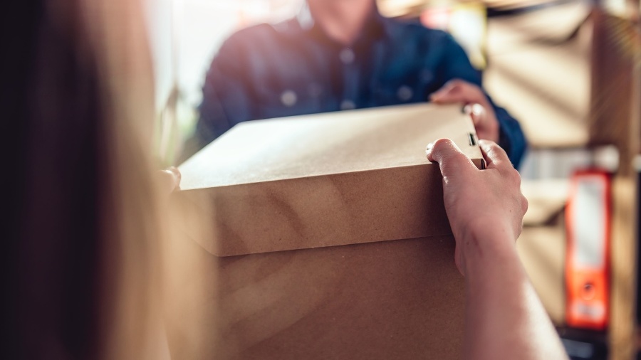 Men wearing blue jean shirt receiving package from courier at the office