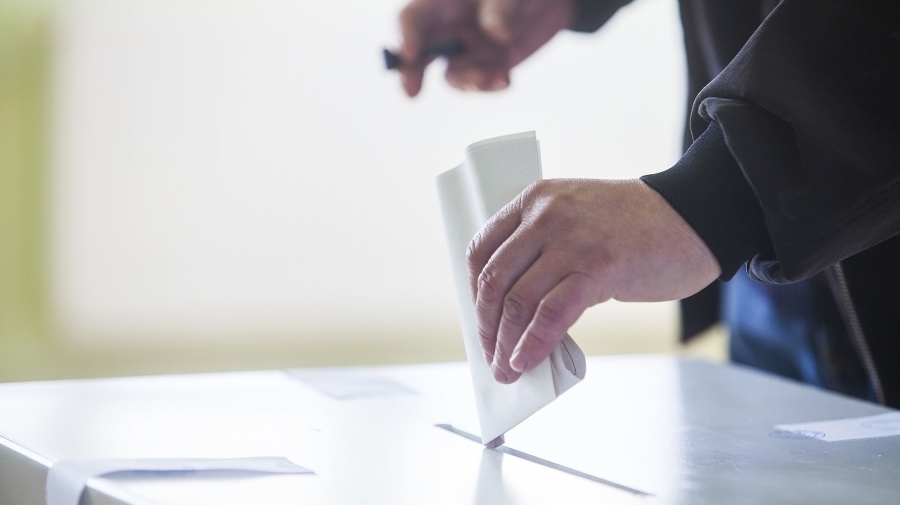 Hand of a person casting a ballot at a polling station during voting.