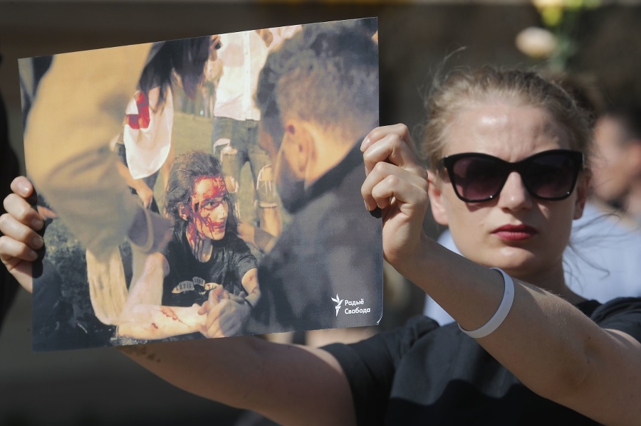 Žena drží fotografiu protestujúceho,