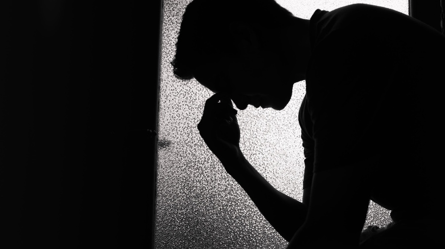 Young sad man sitting in the dark room.