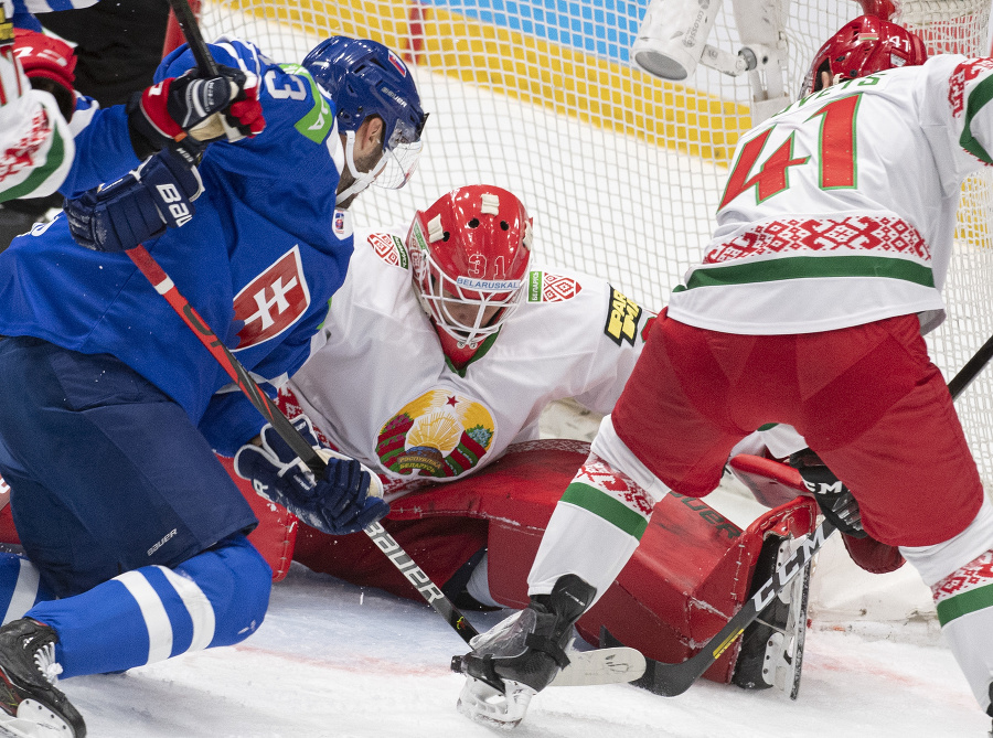 Slovenský hokejista Tomáš Jurčo (vľavo), bieloruský brankár Danny Taylor (uprostred) a bieloruský obranca Kirill Gotovec (vpravo) bojujú o puk v poslednom zápase D-skupiny Slovensko - Bielorusko.
