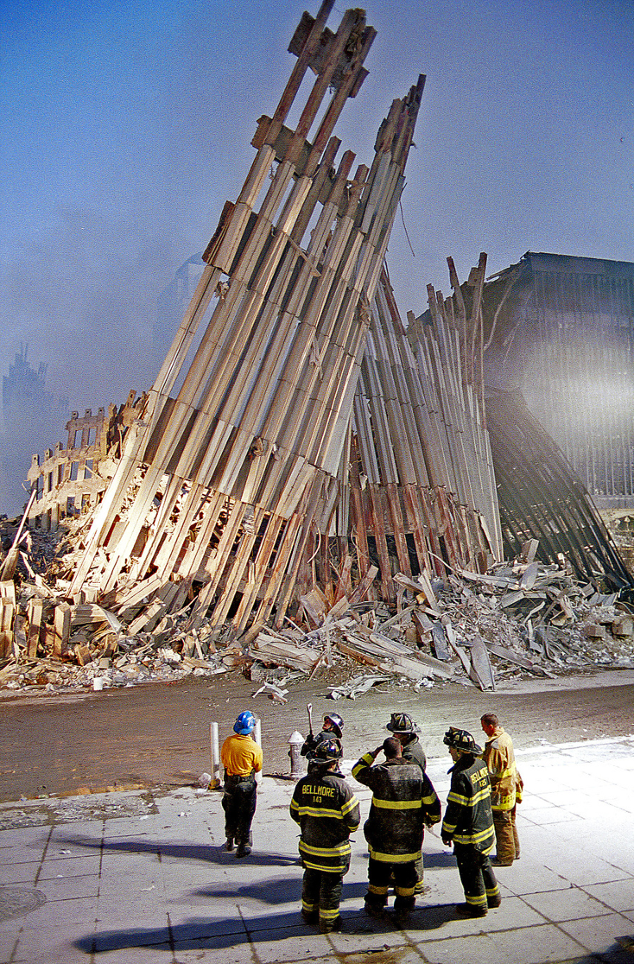 Hasiči sa bezmocne prizerajú na fasádu zrúteného Svetového obchodného centra.