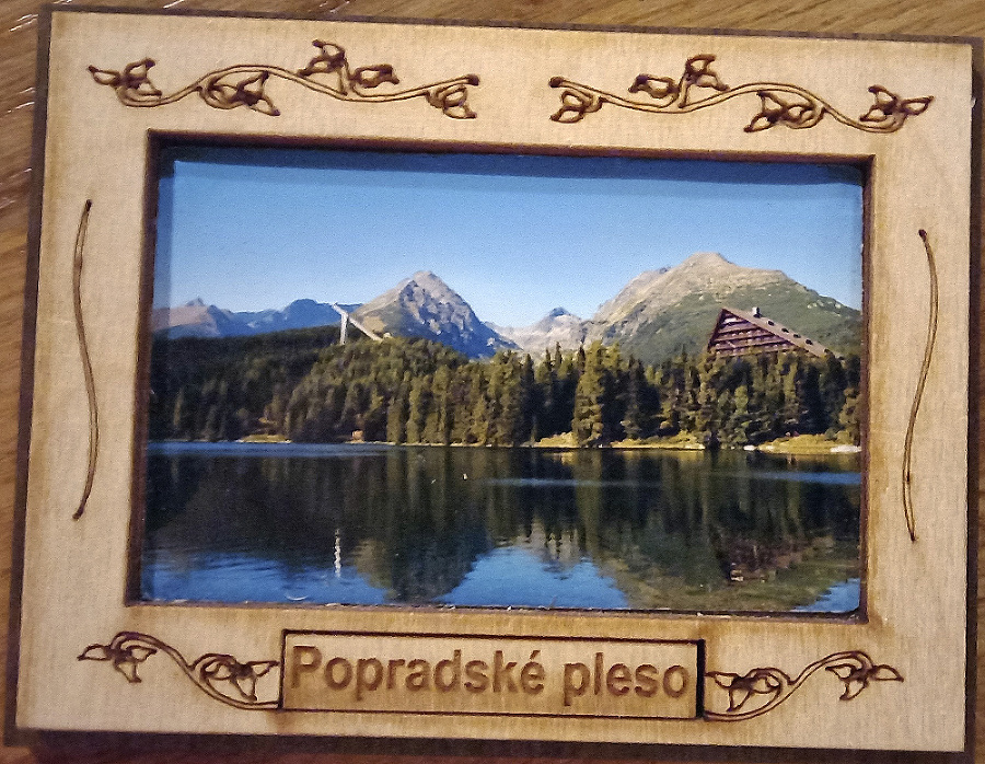 V drevenom rámčeku s nápisom Popradské pleso je umiestnená snímka Štrbského plesa.