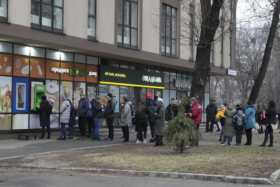 Ľudia čakajú pred bankomatom,