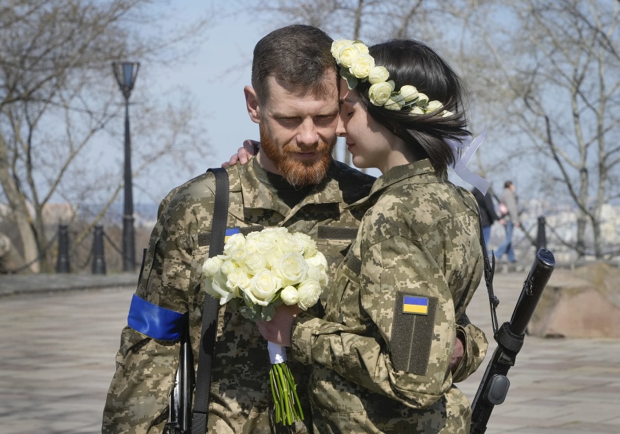 Ukrajinskí vojaci Anastasia a Vjačeslav prežívajú nežnú chvíľu pred ich svadobným obradom v mestskom parku v Kyjeve.