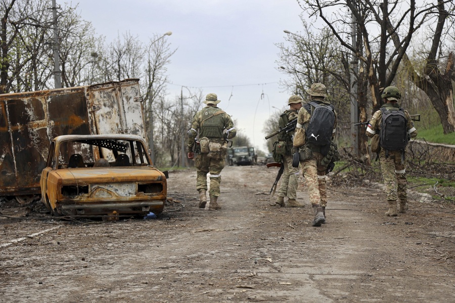 Príslušníci domobrany Doneckej ľudovej republiky kráčajú okolo vrakov áut počas bojov medzi ukrajinskou a ruskou armádou v obliehanom meste Mariupol.