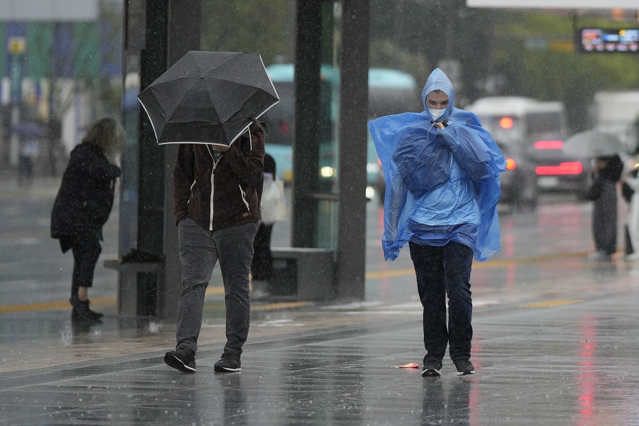 Ľudia kráčajú v daždi