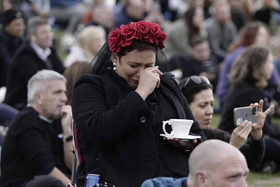 Žena plače, zatiaľ čo na obrazovkách sleduje štátny pohreb britskej kráľovnej Alžbety II.