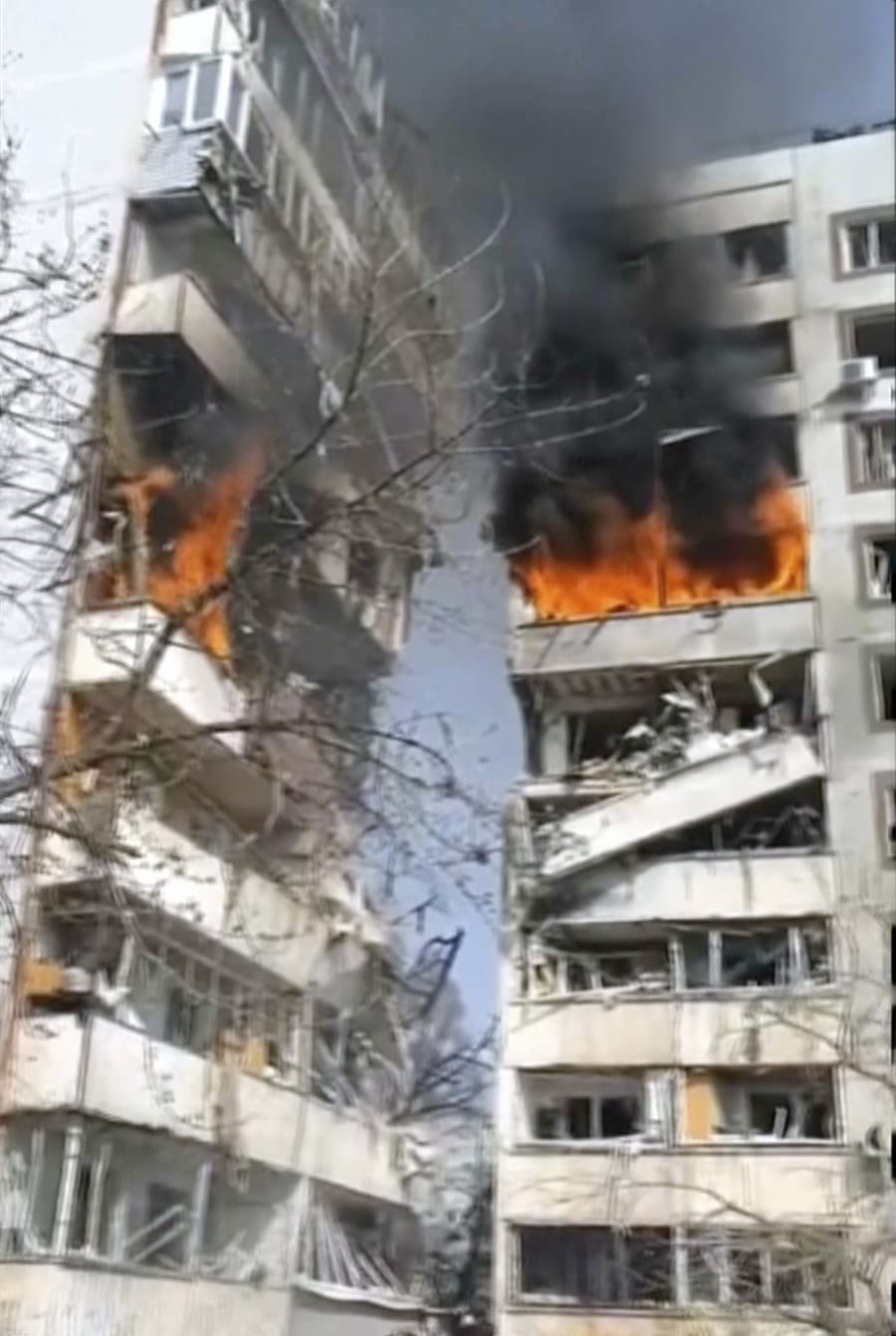 Na videosnímke, ktorú poskytla kancelária ukrajinského prezidenta, ľudia stoja pred horiacou výškovou obytnou budovou, ktorú zasiahlo ostreľovanie v meste Záporožie.