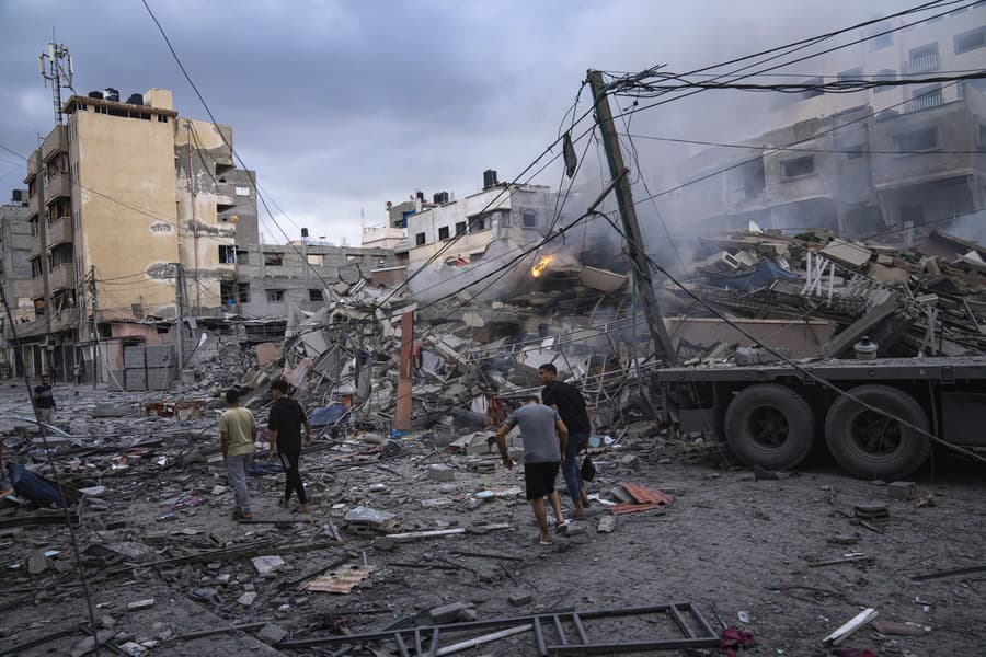  Palestínčania kráčajú medzi ruinami po izraelských leteckých útokoch, ktoré zrovnali so zemou časť štvrte v meste Gaza.