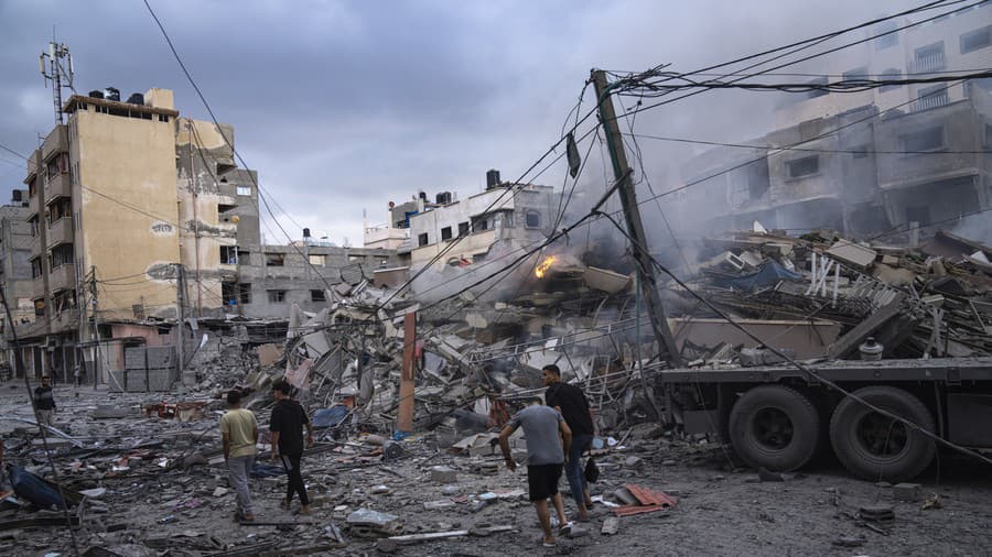  Palestínčania kráčajú medzi ruinami po izraelských leteckých útokoch, ktoré zrovnali so zemou časť štvrte v meste Gaza.