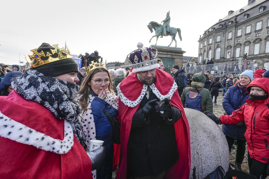 Ľudia oblečení ako kráľ a kráľovná čakajú na zámku Christiansborg v dánskej Kodani.