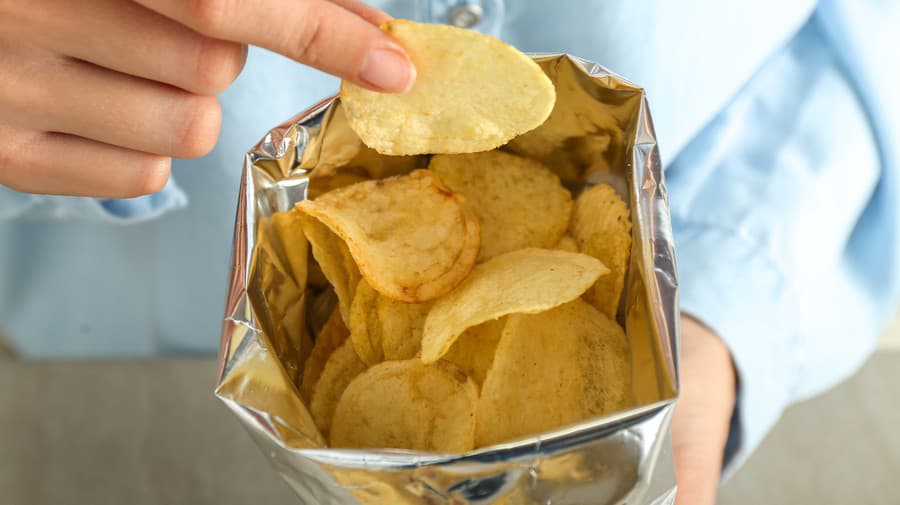 Woman eating tasty potato chips, closeup