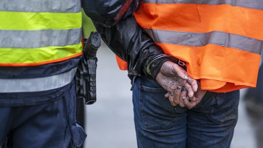 Policajt zatýkajúci klimatického aktivistu.