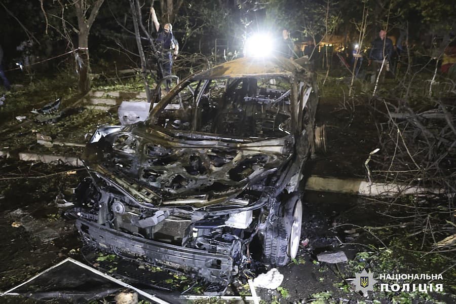 Ľudia svietia na vrak auta po bombovom útoku ruskej armády na obytnú budovu v ukrajinskom meste Charkov v skorých ranných hodinách v nedeľu 22. septembra 2024.