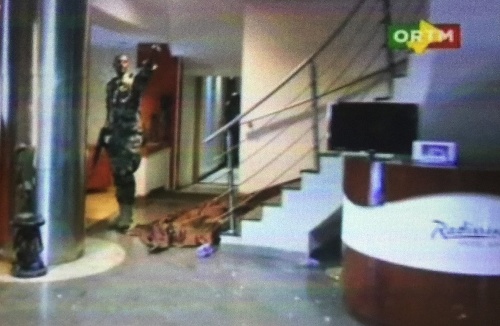 Člen bezpečnostnej jednotky na prízemí hotela Radisson Blu, vedľa neho leží prikryté telo.