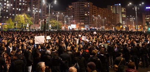 Ľudia stoja na Námestí Víťazstva počas protestu proti vláde v Bukurešti.