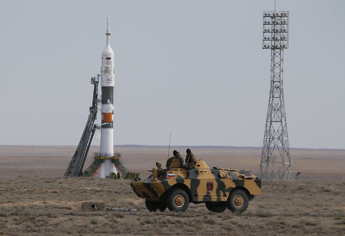 Policajný obrnený trasportét prechádza pred ruskou kozmickou loďou Sojuz TMA-18M pred štartom s tromi astronautmi na palube na kozmodróme Bajkonur.
