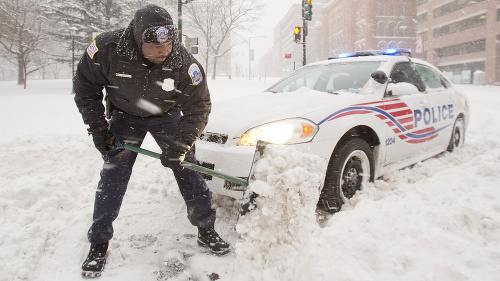 Policajt odhrabáva sneh okolo svojho auta 23. januára 2016 vo Washingtone.